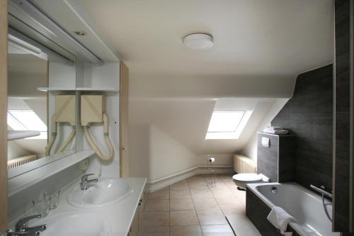 a bathroom with a tub and a sink and a toilet at Hotel Au Prince Royal in Leopoldsburg
