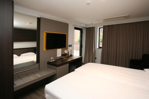 a hotel room with a bed and a television at Hotel Au Prince Royal in Leopoldsburg