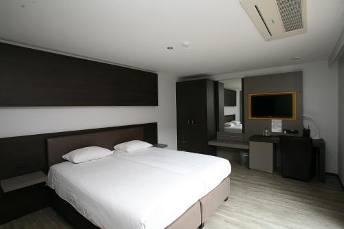 a bedroom with a white bed and a television at Hotel Au Prince Royal in Leopoldsburg