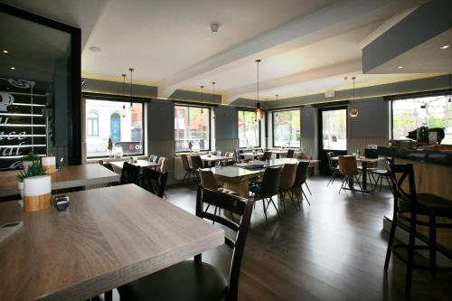 a dining room with tables and chairs and windows at Hotel Au Prince Royal in Leopoldsburg