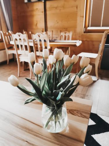 a vase of white tulips sitting on a table at Chaty Misiagi in Poronin