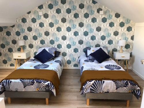 a bedroom with two beds and a geometric wall at Duplex Bastié T3 calme et climatisé WiFi in Lyon