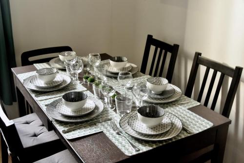 een houten tafel met borden en bekers en wijnglazen bij Duplex Bastié T3 calme et climatisé WiFi in Lyon