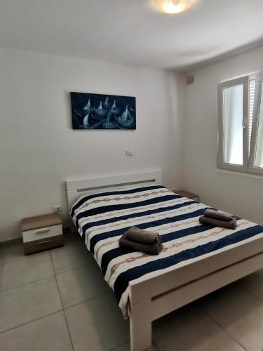 a bed in a white room with two pillows on it at Apartments Victoria in Savudrija