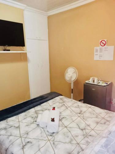 a bedroom with a bed and a tv on a wall at Erins Haven - Polokwane in Polokwane