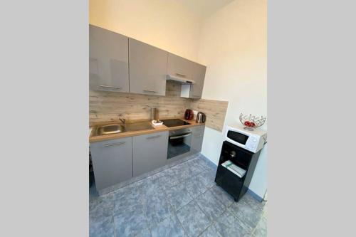 une cuisine avec des armoires blanches, un évier et une cuisinière dans l'établissement Appartement : Le petit paradis de la Loire, à La Charité-sur-Loire