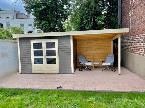 a shed with two chairs and a table in it at Chez Coco Apartment 1 Aachen in Aachen