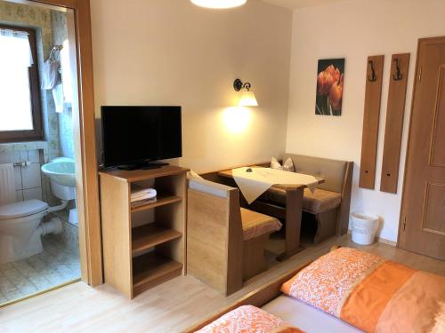 Habitación con baño, cama y TV. en Gästehaus am Kurparkweg, en Reit im Winkl