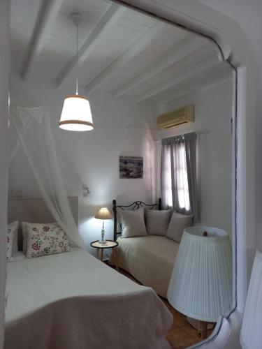 a white bedroom with a bed and a mirror at Stefanos Katsaros Studios in Skala
