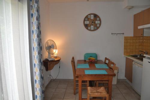 eine Küche mit einem Tisch und Stühlen sowie einer Uhr an der Wand in der Unterkunft Le Hameau du Moulin in Montignac