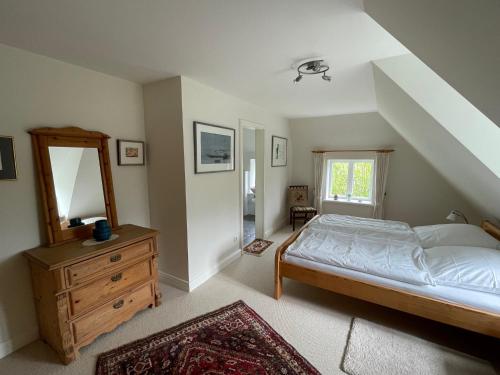 Schlafzimmer mit einem Bett, einer Kommode und einem Spiegel in der Unterkunft Gästehaus Zum Krug in Husum