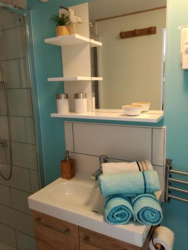 une salle de bain avec un lavabo, un miroir et des serviettes dans l'établissement Les gîtes de 