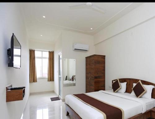 a white bedroom with a large bed and a television at HOTEL SHIV PALACE in Jaipur