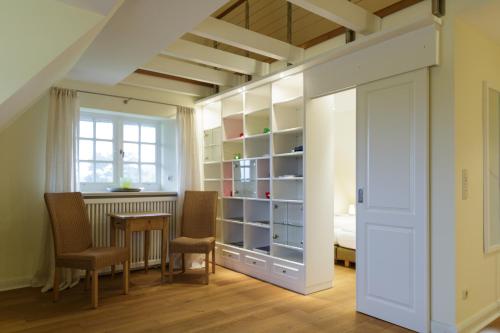 a room with a table and chairs and a closet at Ferienhaus Honigklee im Lüüvhoog in Keitum