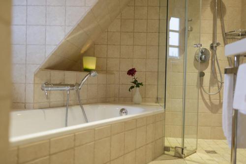 ein Badezimmer mit einer Badewanne und einer Dusche mit Blumen in der Unterkunft Ferienhaus Honigklee im Lüüvhoog in Keitum