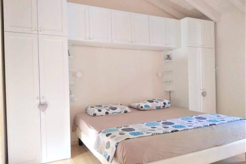 a bedroom with a bed with white cabinets at Serenity Cottage Feriolo in Baveno