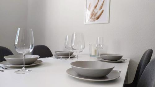 a table with bowls and wine glasses on it at Moderne City Apartments im Stadtzentrum in Kiel