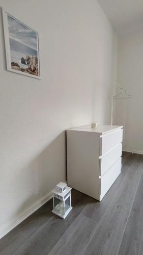 a white dresser in a white room with a stool at Moderne City Apartments im Stadtzentrum in Kiel
