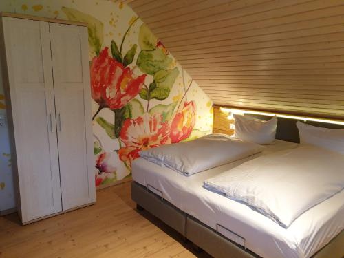 a bedroom with two beds and a wall with flowers at Gästehaus Bartlehof in Schluchsee