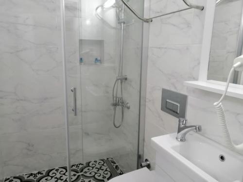 a white bathroom with a shower and a sink at kaktüshan otel in Alaçatı