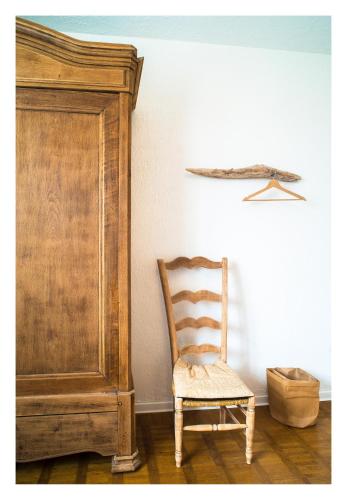 une chaise en bois assise à côté d'un meuble en bois dans l'établissement Chambre soignée et accueillante à la campagne - Ch bleue, à L Honor De Cos