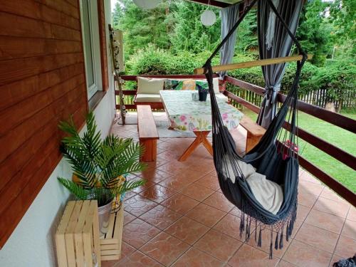 a hammock on a porch of a house at Domek letniskowy "Pod dębem" in Urowo