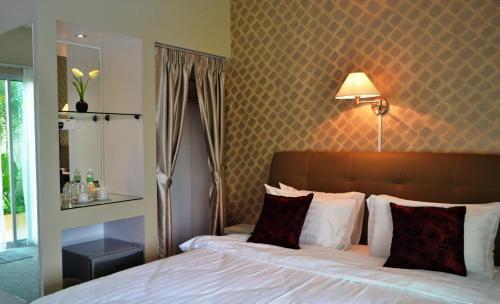 a bedroom with a bed and a lamp on a wall at The Ocean Residence Langkawi in Kuah