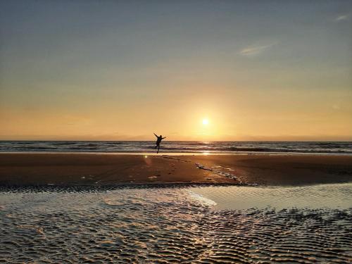 a person standing on the beach with their arms in the air at B&B De Hoffstal in Sassenheim