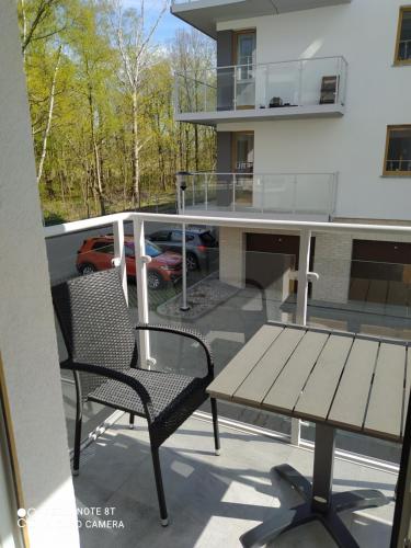 a balcony with a wooden table and a bench at Apartament dla Dwojga - Apartament typu studio in Dziwnówek
