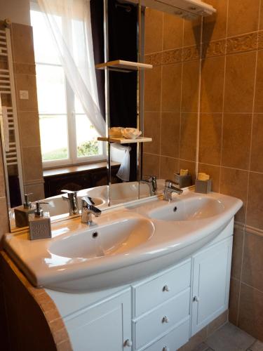 une salle de bain avec deux lavabos et un grand miroir dans l'établissement GITE Les Aubues, à Lormes