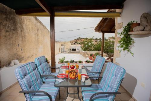 a table with blue chairs on a patio at Maragos Apartment in Pitsidia