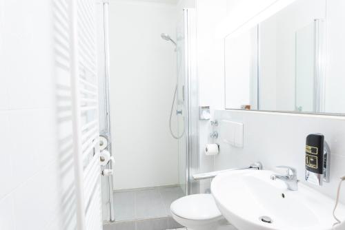 a white bathroom with a toilet and a sink at Hotel Astoria am Urachplatz in Stuttgart