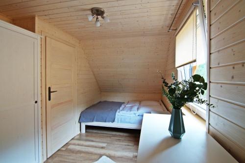 a small bedroom with a bed in a wooden room at Sosnowe Wzgórze in Pasym