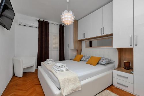 sypialnia z dużym białym łóżkiem i żyrandolem w obiekcie Apartment Sabina w Makarskiej
