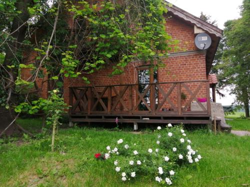 a brick house with a porch and flowers in the grass at Gospodarstwo Agroturystyczne "Dom na kolonii" in Prostki
