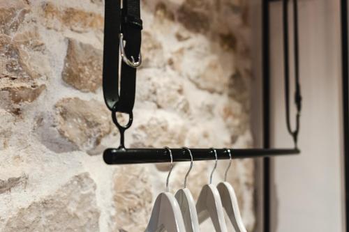 a rack of white hangers in front of a stone wall at Amoretta rooms in Šibenik