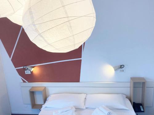 a bedroom with a white bed with a large light fixture at Hotel Nizza Creative Hotel in Rimini