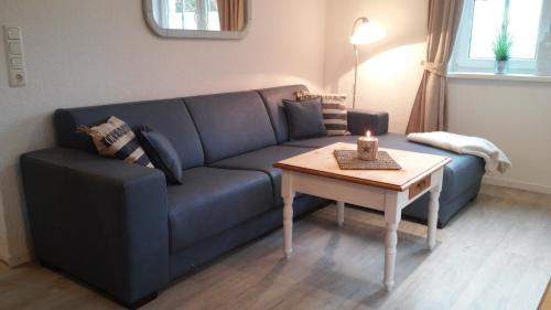 a living room with a blue couch and a table at Fietes Ankerplatz in Wangerland