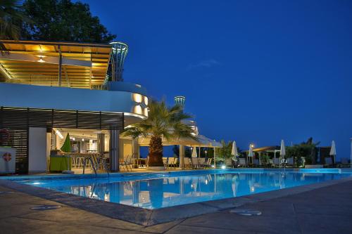 a swimming pool in front of a building at night at Anais Hotel in Korinos