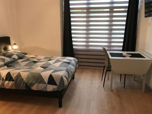 a bedroom with a bed and a desk and a window at Appartements du Vally - Guingamp in Guingamp