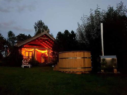 a small house with a barrel in front of it at PO NENDRIŲ STOGU in Šiauliai