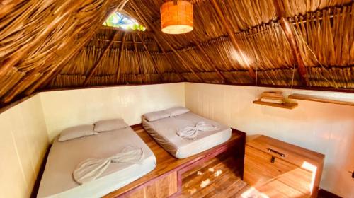 2 camas en una habitación con techo de paja en Los Hermanos Beach Hostal, en Guachaca