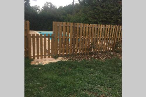 une clôture en bois en face d'une piscine dans l'établissement gite 6 personne, à La Bécade