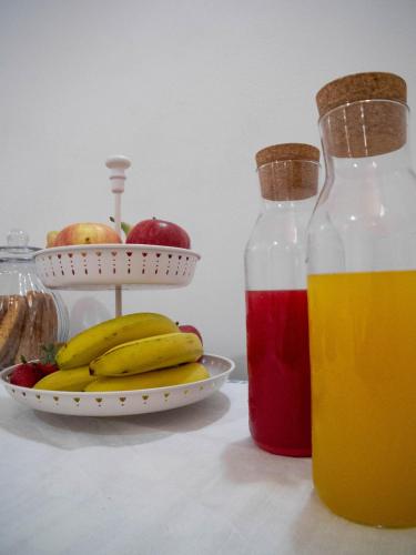 two bottles of juice next to a plate of fruit at Asylum Amicorum Bed & Breakfast in Gagliano del Capo