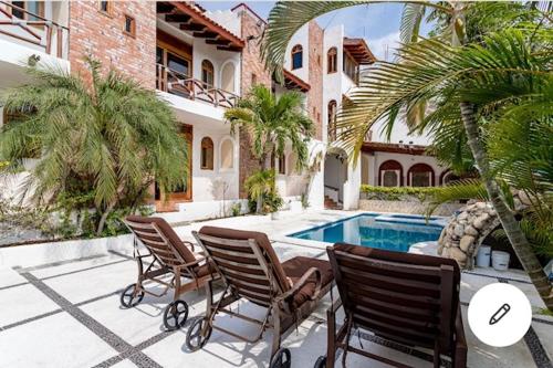 a house with three chairs and a swimming pool at HOTEL VILLAS XAIBA in Puerto Escondido
