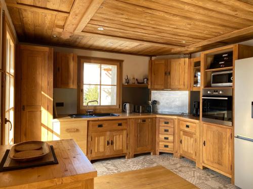 une cuisine avec des armoires en bois et un réfrigérateur blanc dans l'établissement Chalet Le Montana, à Villard-Reculas