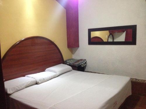 a bedroom with a bed with a wooden headboard and a mirror at Hotel Xalapa in Veracruz