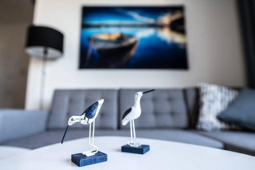 two miniature birds sitting on a table in a living room at Apartament BlueBay in Puck