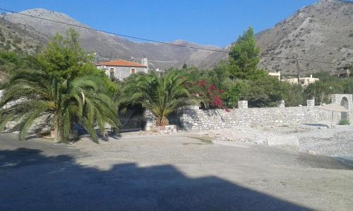 a house with palm trees in front of a stone wall at Ktima Zaxarias in Kokkala