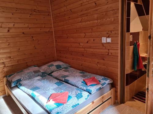a bed in a wooden cabin with two pillows on it at HORSKÝ PENZION U SPLAVU in Josefuv dul